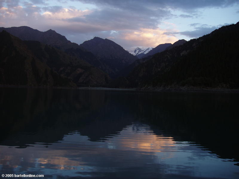 Mountains reflected in the calm evening waters of Tianchi Lake in Xinjiang province, China