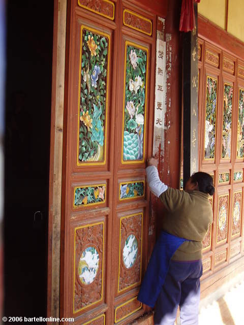 Woman cleans colorful woodwork at the Zhonghe Temple in the Cangshan mountains above Dali, Yunnan, China