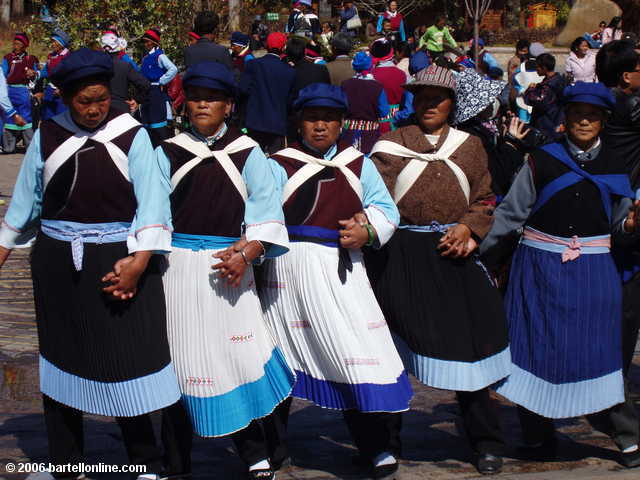 Women in ethnic costume dance in a square in the Old Town section of Lijiang, Yunnan, China