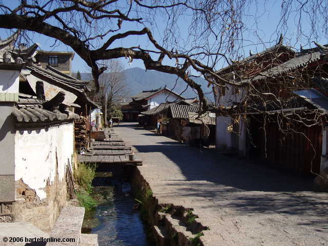 A canal runs along a cobblestone street in the Old Town of Lijiang, Yunnan, China