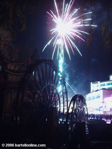 Lunar New Year fireworks above the water wheel at the entrance to the Old Town of Lijiang, Yunnan, China