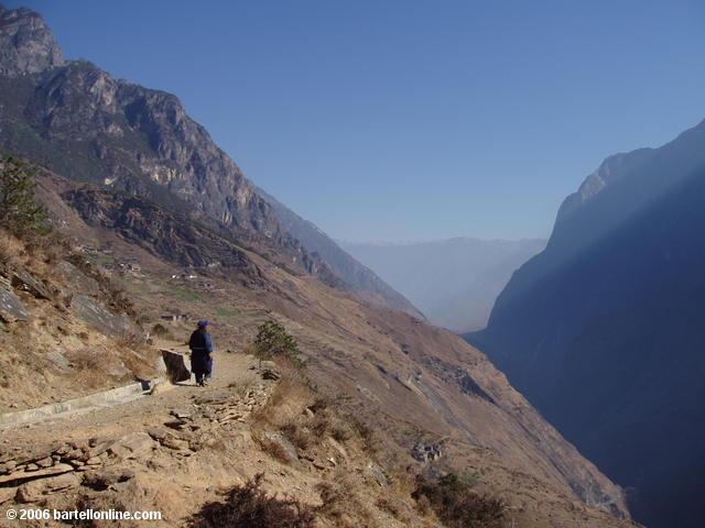 Woman in local minority dress strolls along the upper trail through Tiger Leaping Gorge in Yunnan, China