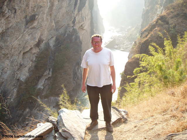 Author poses along a cliffside trail through a narrow section of Tiger Leaping Gorge in Yunnan, China