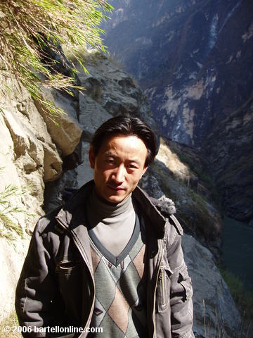 Local toll collector along a narrow cliffside trail through Tiger Leaping Gorge in Yunnan, China