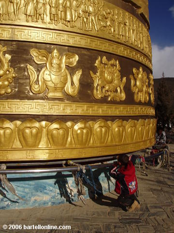 Small boy struggles to turn the giant Buddhist prayer wheel in Zhongdian ("Shangri-La"), Yunnan, China