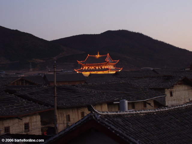 Lighted Buddhist temple seen above roofs in the old town section of Zhongdian ("Shangri-La"), Yunnan, China
